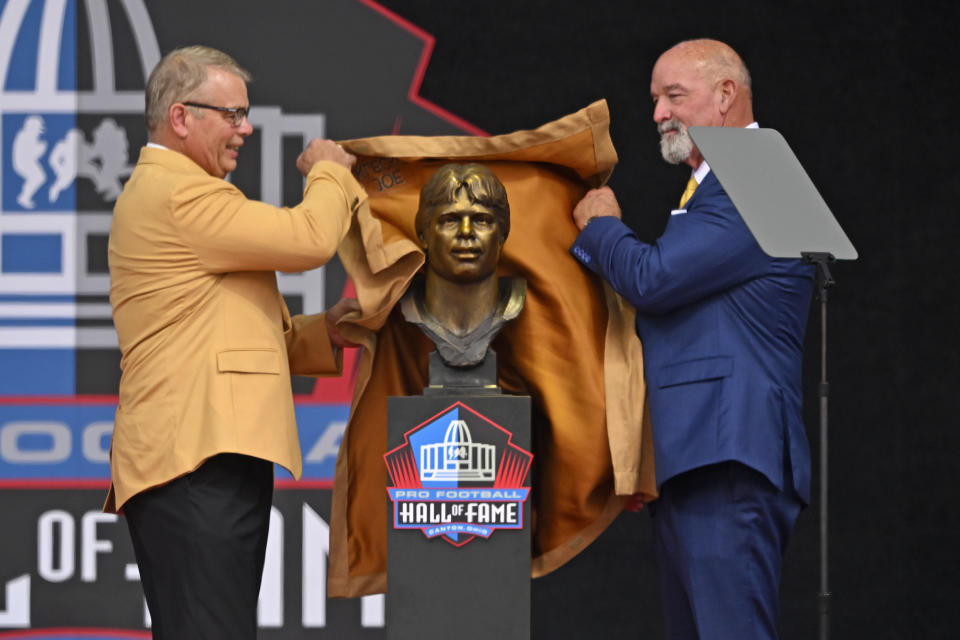 Former NFL player Joe Klecko, left, and former teammate Marty Lyons unveil Klecko's bust during his induction into the Pro Football Hall of Fame, Saturday, Aug. 5, 2023, in Canton, Ohio. (AP Photo David Richard)