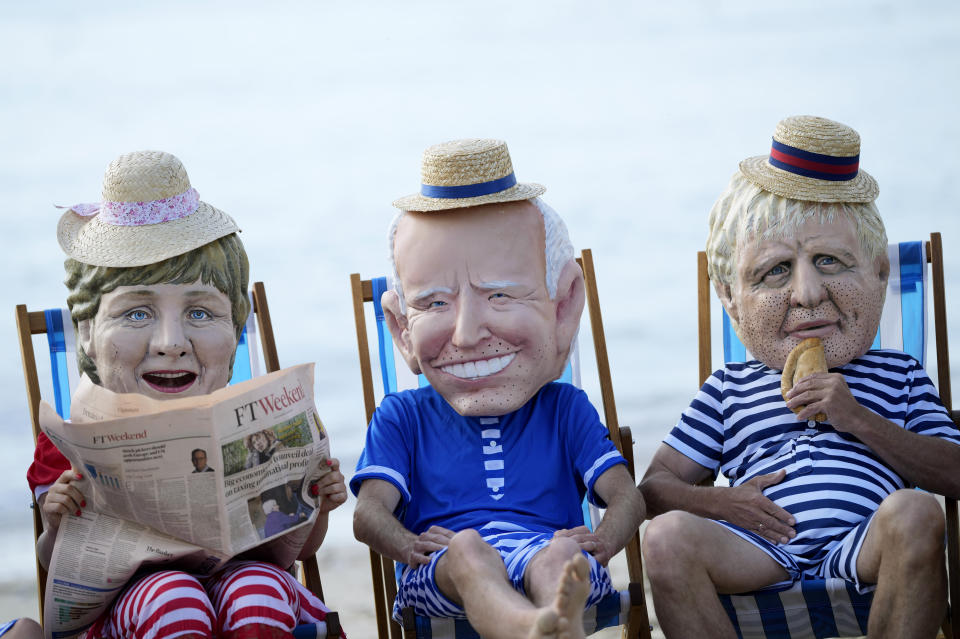 Climate activists from Oxfam, wearing giant heads depicting the leaders of the G7, sit on beach chairs as they participate in an action on Swanpool Beach in Falmouth, Cornwall, England, Saturday, June 12, 2021. Leaders of the G7 gather for a second day of meetings on Saturday, in which they will discuss COVID-19, climate, foreign policy and the economy. Leaders depicted from left, German Chancellor Angela Merkel, U.S. President Joe Biden and British Prime Minister Boris Johnson. (AP Photo/Alastair Grant)