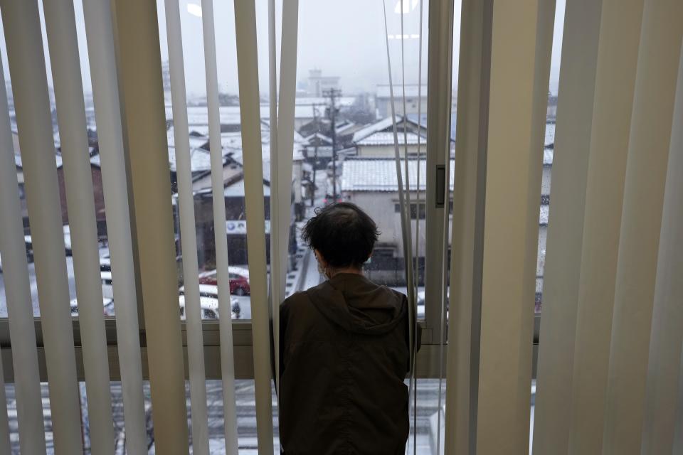 An evacuee from a deadly earthquake looks snow-covered town from the windrow of an evacuation center in Wajima in the Noto peninsula facing the Sea of Japan, northwest of Tokyo, Sunday, Jan. 7, 2024. Monday's temblor decimated houses, twisted and scarred roads and scattered boats like toys in the waters, and prompted tsunami warnings. (AP Photo/Hiro Komae)