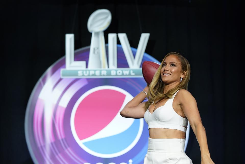 NFL Super Bowl 54 football game halftime performer Jennifer Lopez throws a football at a news conference Thursday, Jan. 30, 2020, in Miami. (AP Photo/David J. Phillip)