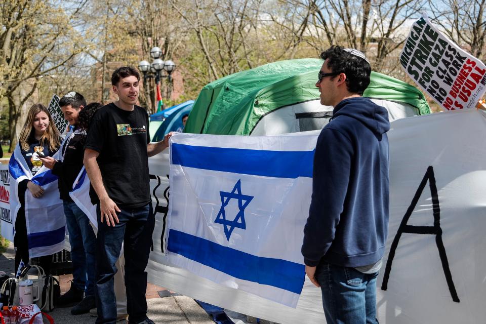 University of Michigan student Tom Sherman, center, talks to recent graduate Adam Kahana as they use their bodies and Israeli flags to cover the word "intifada," which means uprising in Arabic, on a banner that says "Long Live the Intifada" during the encampment for Gaza at UM's Diag in Ann Arbor on Monday, April 22, 2024. The counter-protesters said they were there to condemn antisemitism and support Israel.