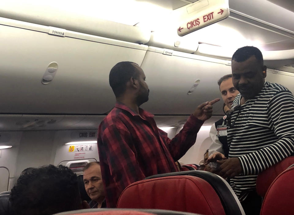 The scene observed by Associated Press photographer Hussein Malla, as an unidentified passenger confronts plane crew members aboard a Turkish Airlines jetliner while in flight from Istanbul, Turkey, Friday June 14, 2019. The unidentified man had to be subdued when he began smashing at an oxygen mask box and damaged a cabin window, before pushing flight attendants aside and rushing toward the cockpit, but then calmed down and after about 2½ hours flying, the pilots announced that the plane was returning to Istanbul.(AP Photo/Hussein Malla)