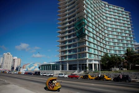 A coco taxi passes by cars line up for gas at the seafront Malecon in Havana