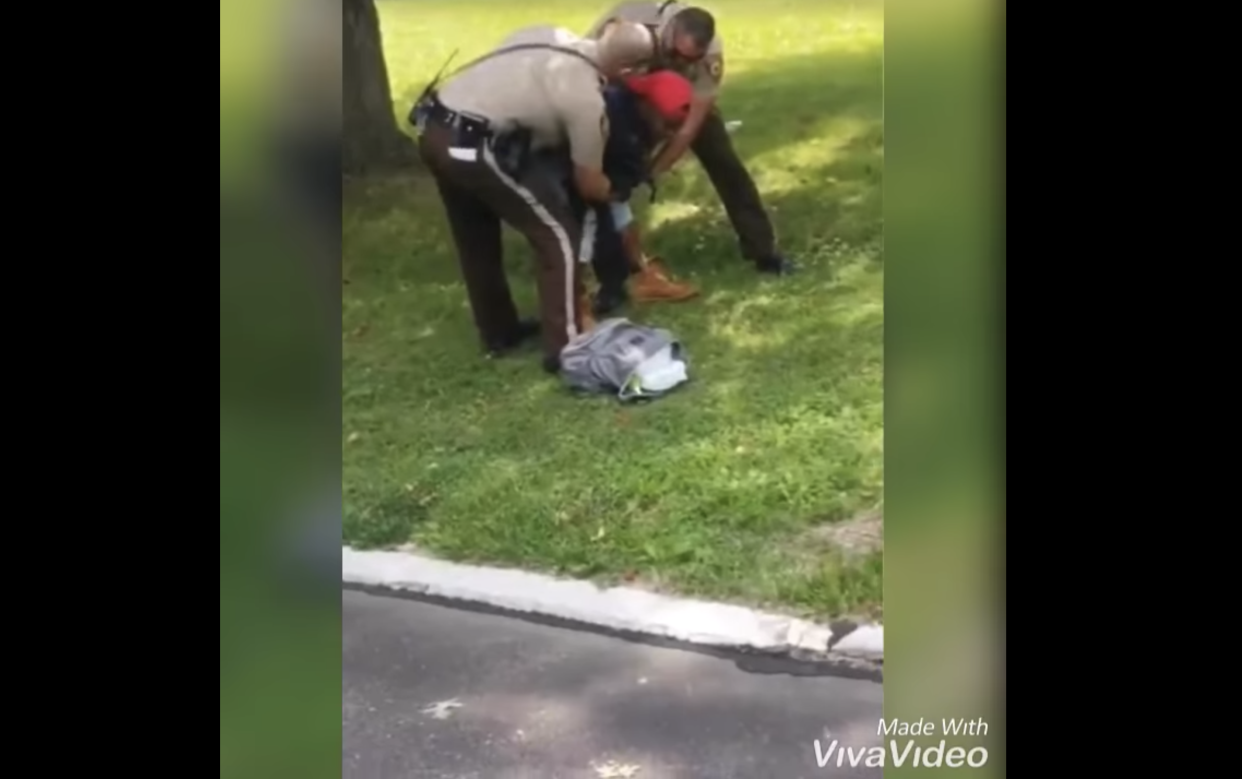 Two officers St. Louis County Police Department in Missouri, tried to forcibly remove an infant from his father's arms, before arresting him on domestic assault charges. (Screenshot: Facebook/Derk Brown)