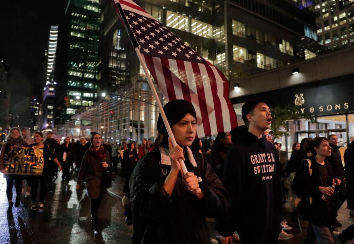 Protests after Donald Trump’s victory A protester carries an upside down American flag as she walks along Sixth Avenue while demonstrating against President-elect Donald Trump, Wednesday, Nov. 9, 2016, in New York. (Photo: Julie Jacobson/AP)