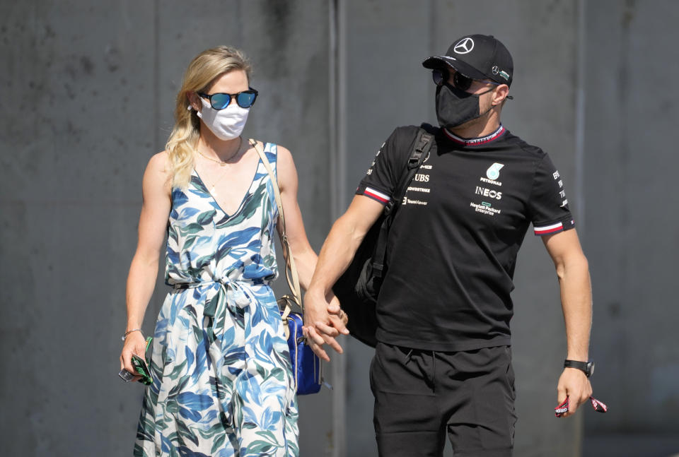 Mercedes driver Valtteri Bottas of Finland, right, with his girlfriend Tiffany Cromwell arrives at the Hungaroring racetrack ahead of the first free practice, in Mogyorod, Hungary, Friday, July 30, 2021. The Hungarian Formula One Grand Prix will be held on Sunday. (AP Photo/Darko Bandic)