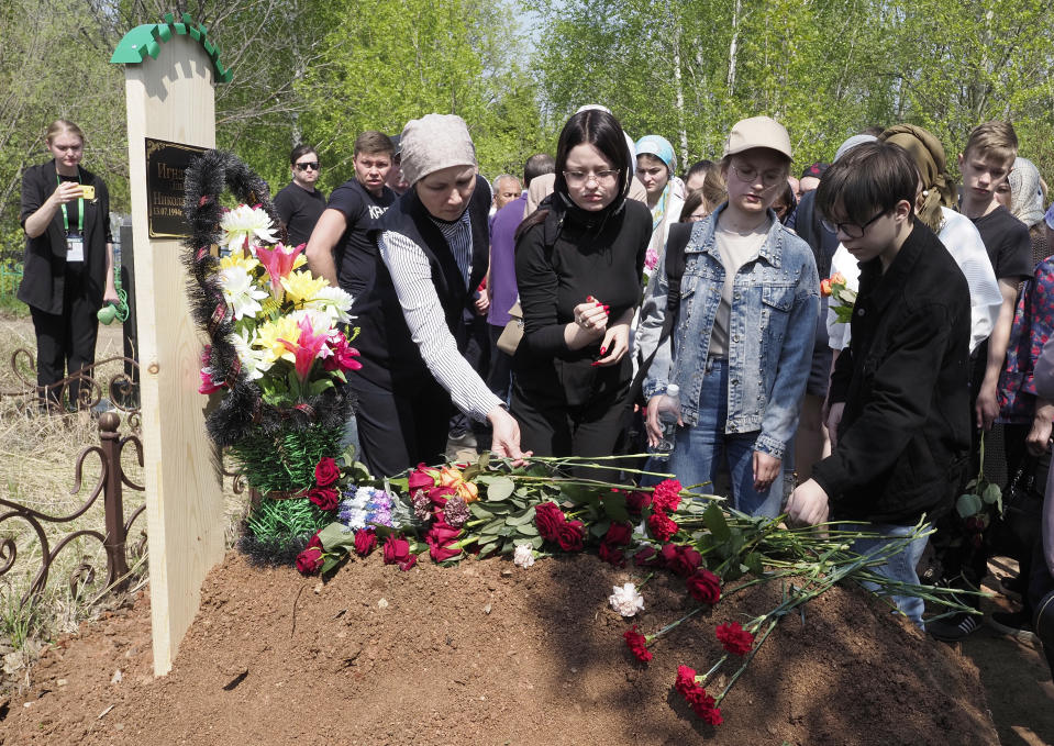 People lay flowers at the grave of Elvira Ignatieva, an English language teacher, who was killed at a school shooting on Tuesday in Kazan, Russia, Wednesday, May 12, 2021. Russian officials say a gunman attacked a school in the city of Kazan and Russian officials say several people have been killed. Officials said the dead in Tuesday's shooting include students, a teacher and a school worker. Authorities also say over 20 others have been hospitalised with wounds. (AP Photo/Dmitri Lovetsky)
