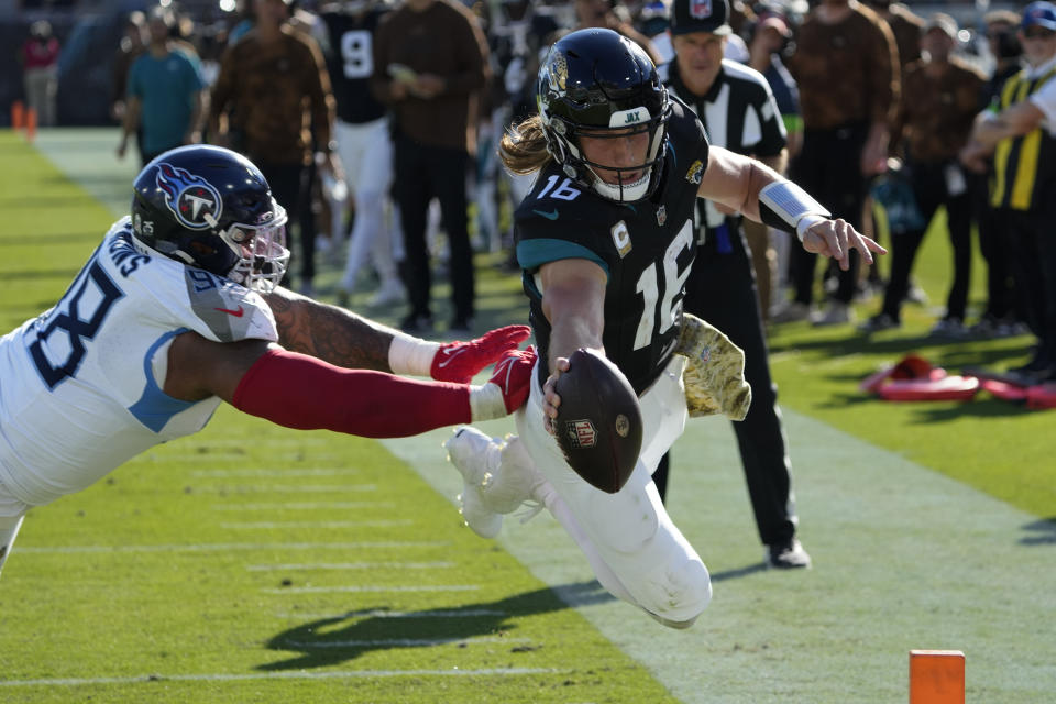 Jacksonville Jaguars quarterback Trevor Lawrence (16) dives for a touchdown past Tennessee Titans defensive tackle Jeffery Simmons, left, during the second half of an NFL football game, Sunday, Nov. 19, 2023, in Jacksonville, Fla. (AP Photo/John Raoux)