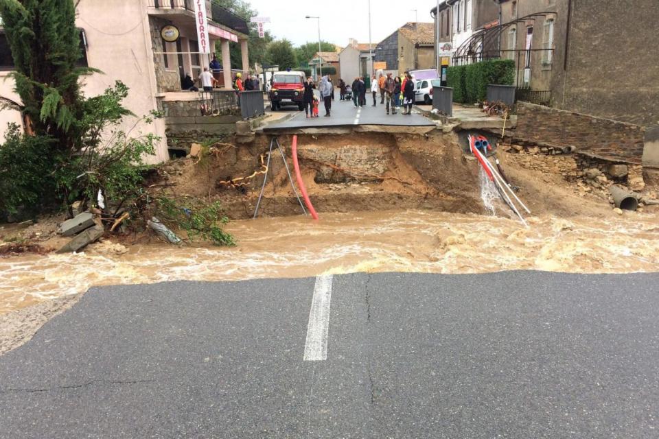 People stand on the road over the Trapel river that collapsed during the heavy rain (AFP/Getty Images)