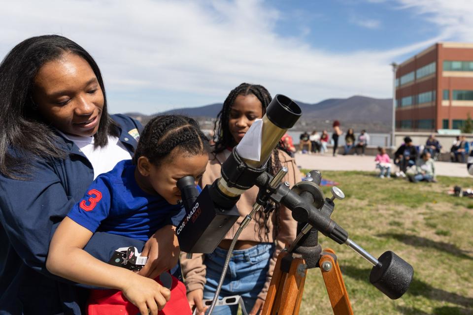 Kenisha Scott, left Khyree Scott 8, center and Kamirah Scott 11, right view the partial solar eclipse through a telescope with a solar filter SUNY Orange in Newburgh, NY on April 8, 2024.
