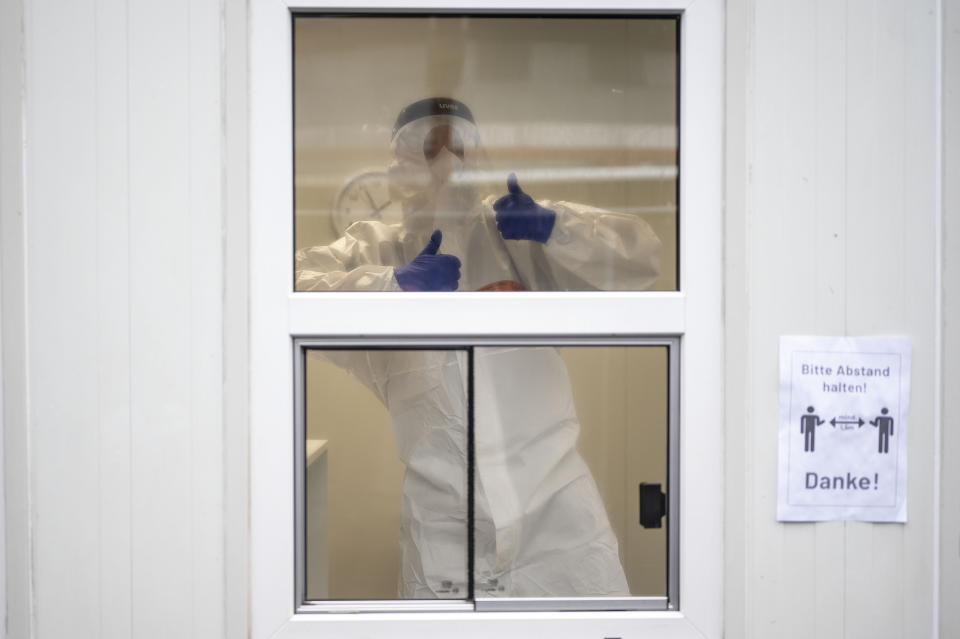 An employee shows thumbs-up inside a container at the test center for the coronavirus at Central Station in Cologne, Germany, Friday, Oct. 23, 2020. According to the Robert Koch Institute, Germany's federal government agency and research institute responsible for disease control and prevention, the number of new infections with the corona virus in Cologne has risen to 120.1 per 100,000 inhabitants. (Marius Becker/dpa via AP)