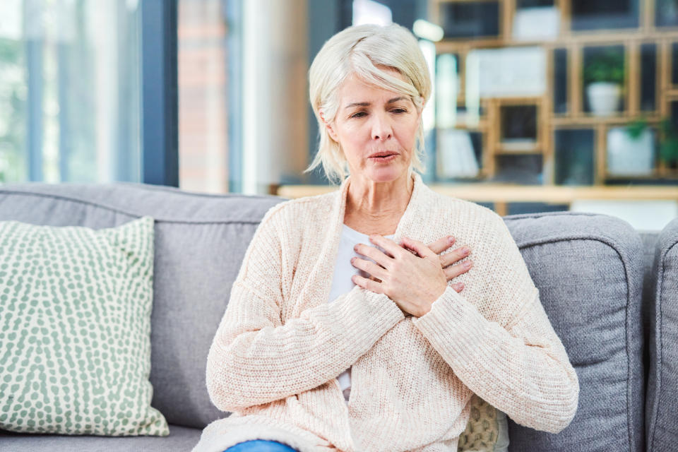 Shot of a woman suffering from chest pain while sitting on the sofa at home. (Getty Images)