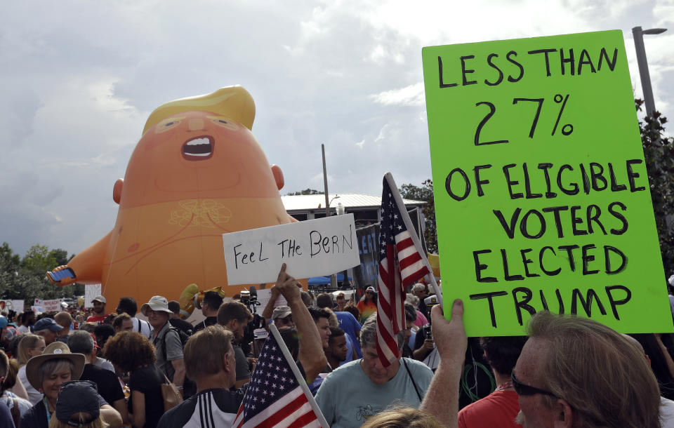 A group of protestors watch as a Baby Trump balloon is inflated during a rally Tuesday, June 18, 2019, in Orlando, Fla., near where President Donald Trump was announcing his re-election campaign. President Trump is being trolled by an angry diaper-clad caricature armed with a cell phone. It’s Baby Trump, the blimp that has become synonymous with resistance to the American president. The balloon has been cloned multiples times over and become something of a celebrity _ for at least one slice of the U.S. electorate. He’s also emerged as a rallying point for supporters of the president who see the blimp as evidence of just how over-the-top the opposition has become.(AP Photo/Chris O'Meara)