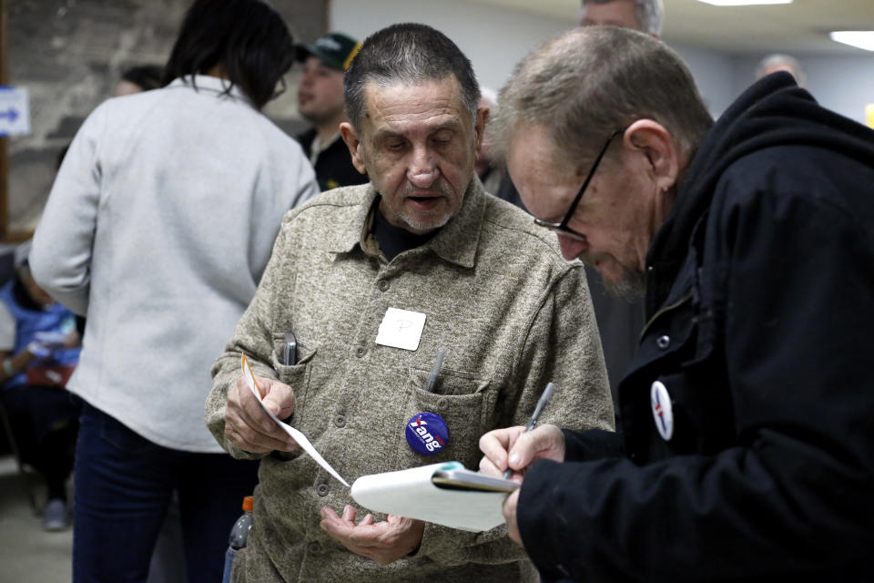 David, left, and Mike Fuerstenberg fill out their presidential preference cards during the Democratic caucus at the UAW Hall in Dubuque, Iowa on Monday, Feb. 3, 2020. (Eileen Meslar/Telegraph Herald via AP)
