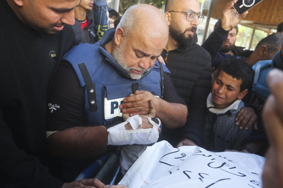 Al Jazeera journalist Wael Dahdouh holds the hand of his son Hamza, who also worked for Al Jazeera and who was killed in an Israeli airstrike in Rafah, Gaza Strip, Sunday, Jan. 7, 2024. Dahdouh lost his wife, two other children and a grandson earlier in the war and was nearly killed himself. (AP Photo/Hatem Ali)