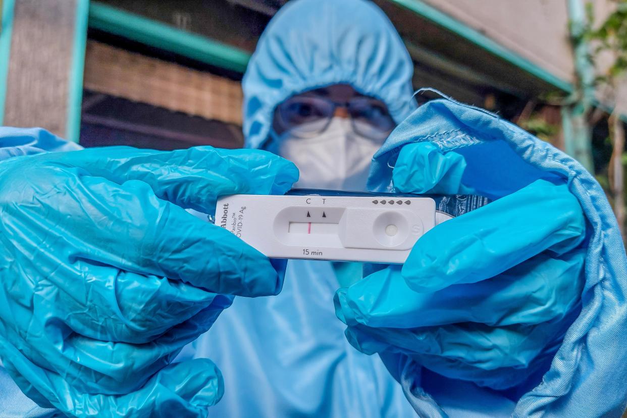 A medical worker shows a negative COVID-19 antigen test result during an at-home COVID-19 antigen testing in Quezon City, the Philippines on Jan. 10, 2022. The Philippines reported 33,169 new COVID-19 infections on Monday, a new record daily spike, pushing the number of confirmed cases in the Southeast Asian country to 2,998,530. (Photo by Rouelle Umali/Xinhua via Getty Images)