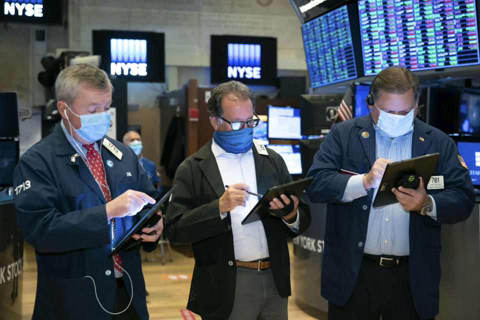 In this photo provided by the New York Stock Exchange, traders James Lamb, Sal Suarino and John Santiago, left to right, work on the trading floor, Thursday Dec. 3, 2020. U.S. stocks are inching further into record heights Thursday, as Wall Street continues to coast following its rocket ride last month powered by hopes for coming COVID-19 vaccines. (Nicole Pereira/New York Stock Exchange via AP)