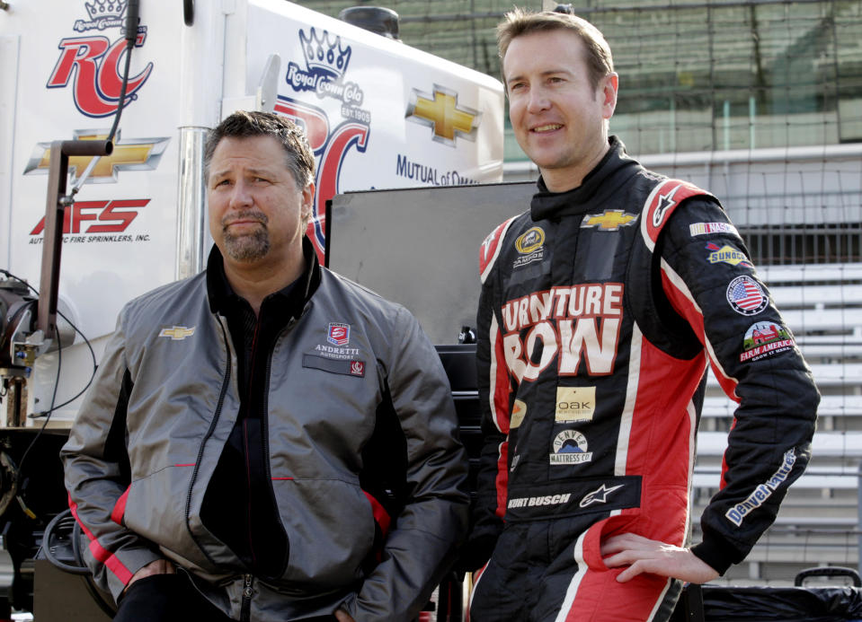 FILE - In this May 9, 2013 file photo, Andretti Autosport team owner Michael Andretti, left, and NASCAR driver Kurt Busch wait for the start of a testing session at the Indianapolis Motor Speedway in Indianapolis. Kurt Busch and Andretti Autosport announced Tuesday, March 4, 2014, that he will try to become the first driver in 10 years to run the Indianapolis 500 and the Coca-Cola 600 on the same day. (AP Photo/AJ Mast, File)