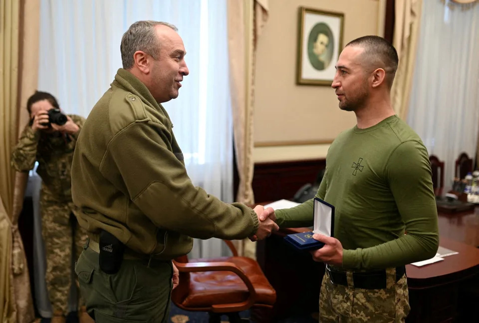 Ukrainian service member Roman Gribov shakes hands with the head of Cherkasy Regional Military Administration Ihor Taburets.