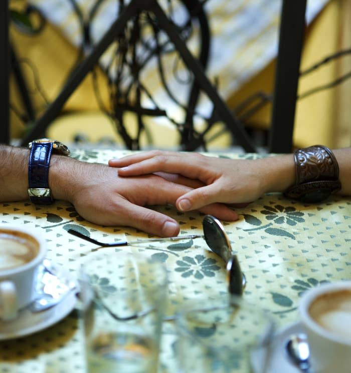 Woman's hand on top of man's hand on table in a café