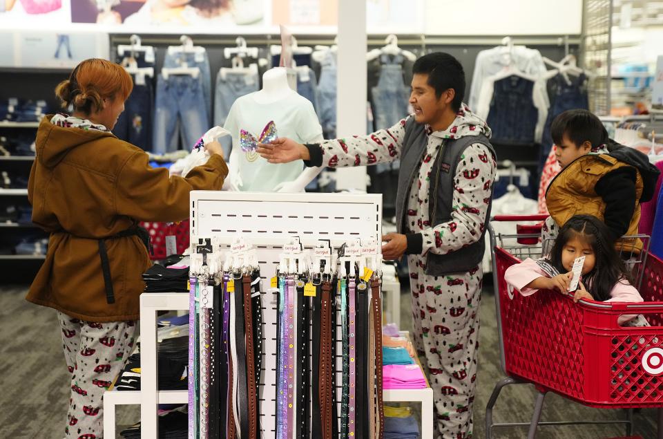 LeKenroy Massey hands Ashley Suttle an item as they shop with their children Kalcifer and Marceline during a $1,000 shopping spree for poverty-level families at Target.