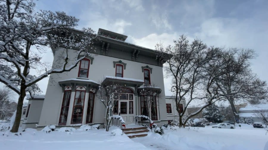 An exterior photo of the Sweet House on a sunny, but cold winter day. The house is painted white with gray and burgundy trim.