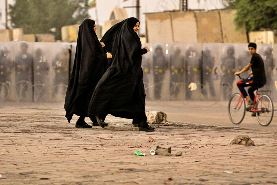 Women rush towards the protest site while Security forces surround the protest site during ongoing anti-government protests in Basra, Iraq, Wednesday, Nov. 4, 2020. (AP Photo/Nabil al-Jurani