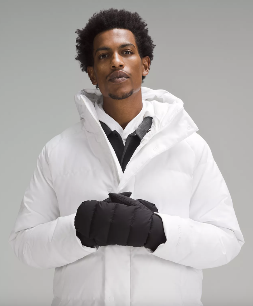 black man wearing white puffer jacket and black gloves, Wunder Puff Mittens (Photo via Lululemon)