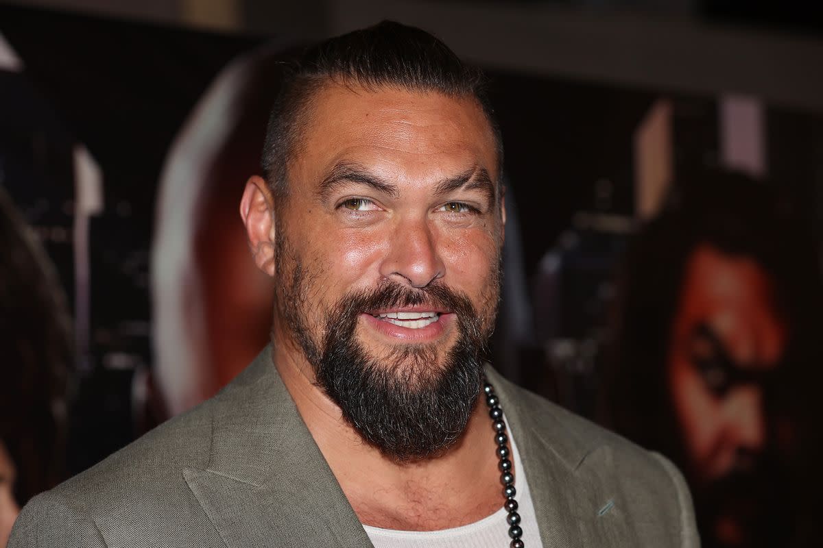 A Polynesian man with a beard wearing a gray suit is photographed smiling. Fiona Goodall/Getty Images for Universal Pictures