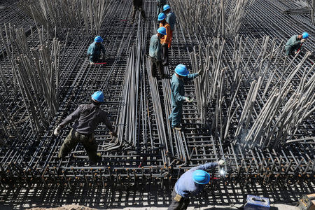 FILE PHOTO: Workers are seen amid steel bars at a construction site of a highway in Zhaotong, Yunnan province, China April 20, 2018. Picture taken April 20, 2018. REUTERS/Stringer/File Photo