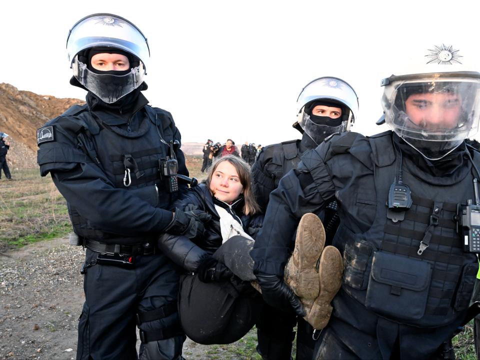 Police officers carry Swedish climate activist Greta Thunberg away from the edge of the Garzweiler II opencast lignite mine (AP)