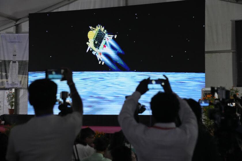 Journalists film the live telecast of spacecraft Chandrayaan-3 landing on the moon at ISRO's Telemetry, Tracking and Command Network facility in Bengaluru, India, Wednesday, Aug. 23, 2023. India lands a spacecraft near the moon's south pole, becoming the fourth country to touch down on the lunar surface. (AP Photo/Aijaz Rahi)