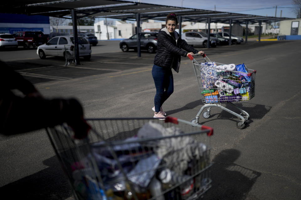 Uruguayan Diana Rocco heads to her car with a full shopping cart outside a super market in Gualeguaychu in the province of Entre Rios, Argentina, Friday, June 30, 2023. From the Uruguayan town of Palmitas, Rocco said she plans to return to Gualeguaychú because her salary as a security guard is barely enough to cover her expenses back home. (AP Photo/Natacha Pisarenko)