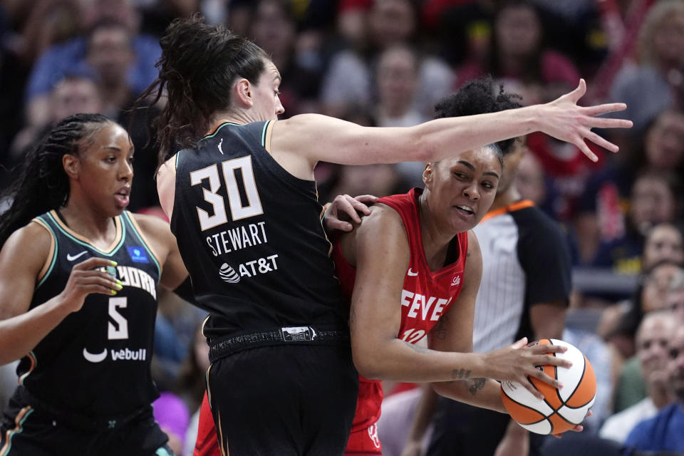 Indiana Fever's Damiris Dantas (12) makes a pass against New York Liberty's Breanna Stewart (30) and Kayla Thornton (5) during the first half of a WNBA basketball game, Saturday, July 6, 2024, in Indianapolis. (AP Photo/Darron Cummings)