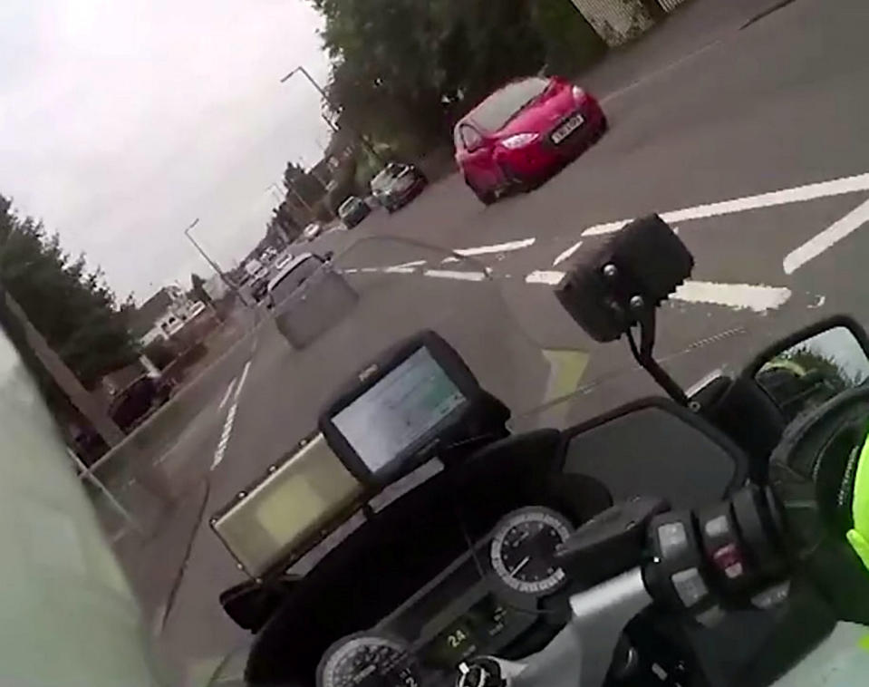 A teenage yob is facing jail after shocking footage caught him ramming a police officer off his motorbike in a stolen car. Callum Fellows, 18, was behind the wheel of a dark blue Seat Leon which was being followed by PC Steve Lovering. When the car stopped at traffic lights the officer drove up to the driver's door but Fellows suddenly reversed before steering straight into PC Lovering's BMW bike. CCTV and the officer’s body-cam captured the shocking moment when PC Lovering was sent sprawling onto Ashes Road in Oldbury, West Mids. The officer is heard shouting out in pain before radioing colleagues for help as Fellows sped away.