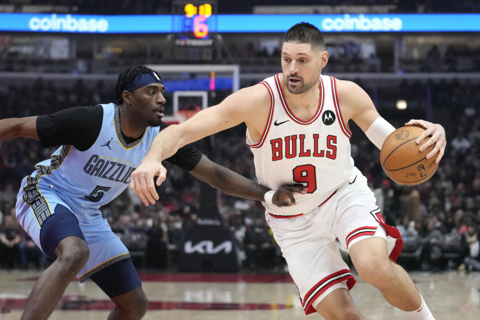 Chicago Bulls' Nikola Vucevic (9) drives as Memphis Grizzlies' Vince Williams Jr. defends during the first half of an NBA basketball game Saturday, Jan. 20, 2024, in Chicago. (AP Photo/Charles Rex Arbogast)