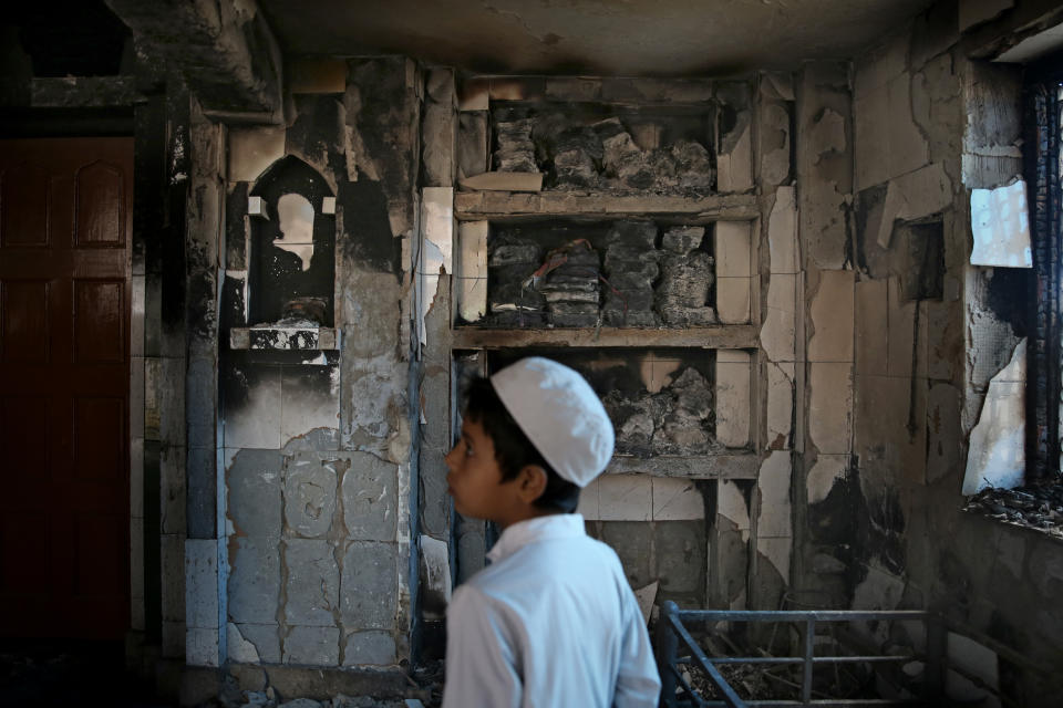 FILE - In this Thursday, Feb. 27, 2020, file photo, an Indian Muslim boy stands inside a mosque burnt in Tuesday's communal violence in New Delhi, India. As the first anniversary of bloody communal riots that convulsed the Indian capital approaches, Muslim victims are still shaken and struggling to make sense of their struggle to seek justice. Many say they have run repeatedly into a refusal by police to investigate complaints made by Muslims against Hindu rioters. (AP Photo/Altaf Qadri)