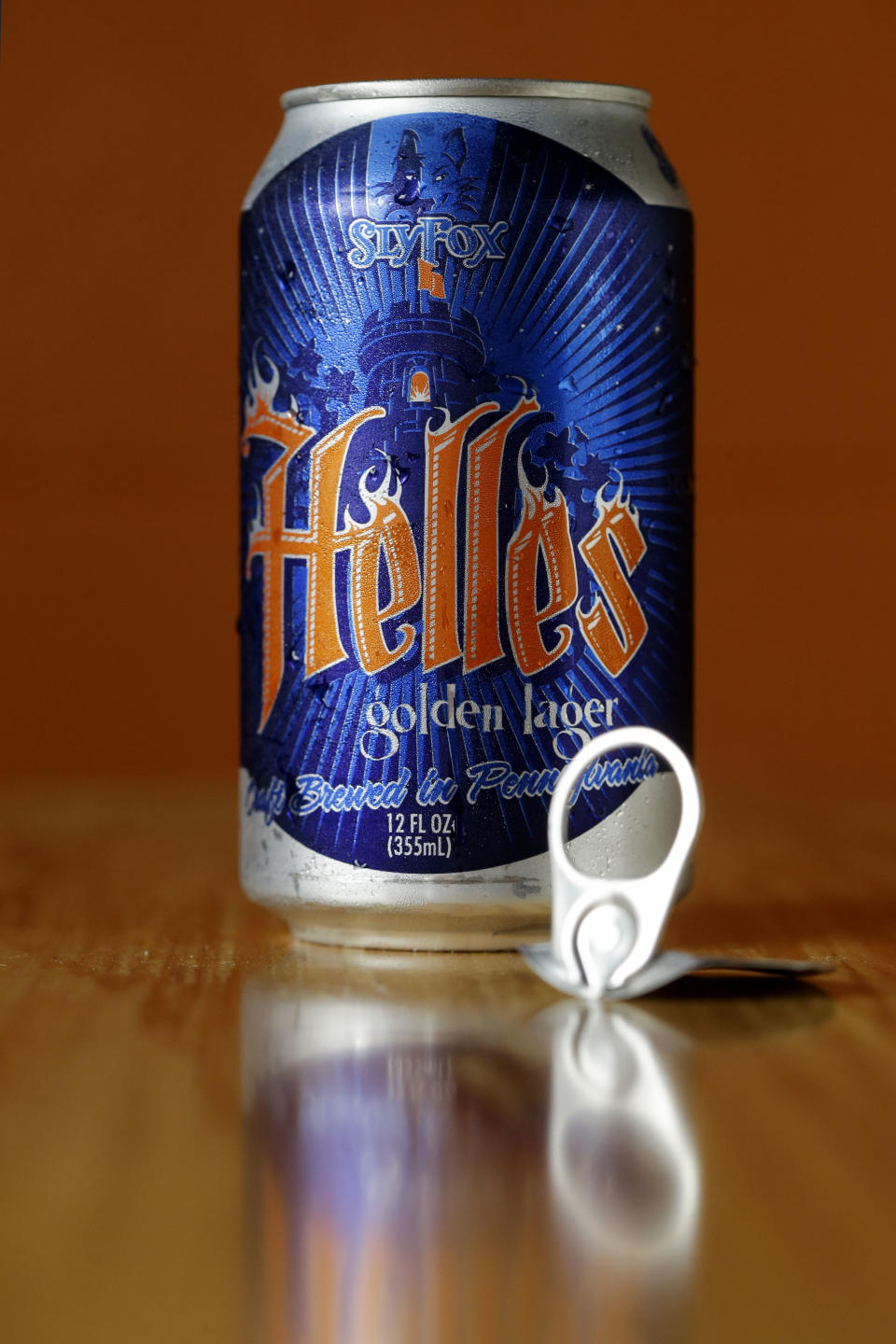 In this Monday, June 3, 2013 photo, a can of Helles Golden Lager with a 360 Lid is displayed at the Sly Fox Brewing Company, in Pottstown, Pa. Brewers and consumers debate using bottles or cans, innovation of the age-old staple continues as breweries seek to differentiate themselves on expanding beer shelves. Budweiser is selling a bowtie-shaped can that mirrors its iconic logo, Miller Lite is sold in a punch-top can, Sam Adams Boston Lager comes in cans designed to improve taste and now Sly Fox Brewing Co. is selling beer in "topless" cans with a peel-back lid that essentially turns it into a glass. (AP Photo/Matt Rourke)