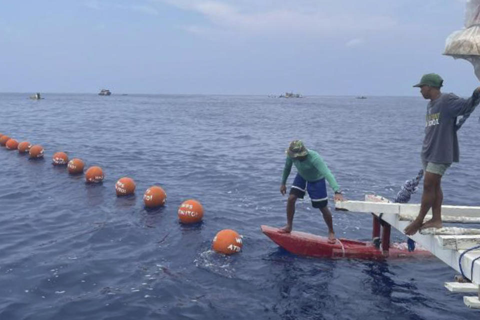 In this photo provided by Atin-Ito/Akbayan Party, belonging to a nongovernment coalition called Atin Ito, Tagalog for This is Ours, place symbolic bouys in the waters off Palauig Point, Zambales province, northwestern Philippines before heading towards Scarborough Shoal on Wednesday May 15, 2024. A flotilla of about 100 mostly small fishing boats led by Filipino activists sailed Wednesday to a disputed shoal in the South China Sea, where Beijing's coast guard and suspected militia ships have used powerful water cannons to ward off what they regard as intruders. (Atin-Ito/Akbayan Party via AP)