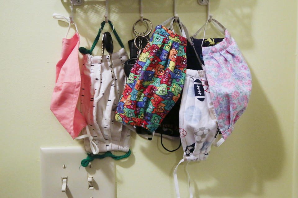 Face coverings hang on hooks along with keys by the front door of the Adamus family on Monday, Aug. 3, 2020, in Dallas, Ga. The Adamus children are among tens of thousands of students in Georgia and across the nation who were set to resume in-person school Monday for the first time since March. (AP Photo/Brynn Anderson)