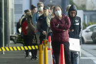 People queue early morning outside a supermarket in Hobsonville, Auckland, as New Zealand prepares to move into Covid-19 Alert Level 3, Wednesday, Aug. 12, 2020. New Zealand Prime Minister Jacinda Ardern said Tuesday, Aug. 11 authorities have found four cases of the coronavirus in one Auckland household from an unknown source, the first reported cases of local transmission in the country in 102 days. (Dean Purcell/New Zealand Herald via AP)