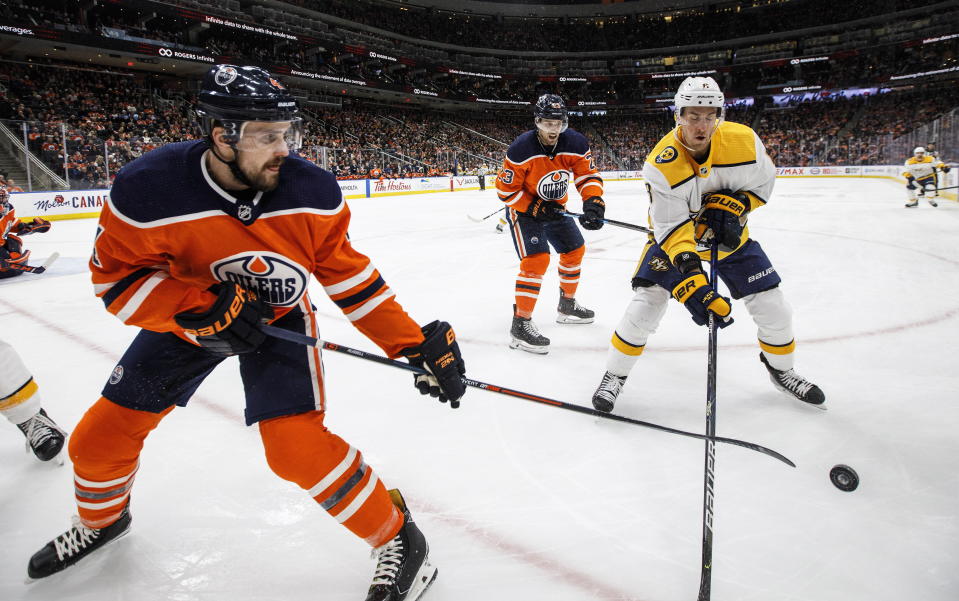 Nashville Predators' Kyle Turris (8) and Edmonton Oilers' Kris Russell (4) battle for the puck during third period NHL hockey action in Edmonton, Alberta, Tuesday, Jan. 14, 2019. (Jason Franson/The Canadian Press via AP)