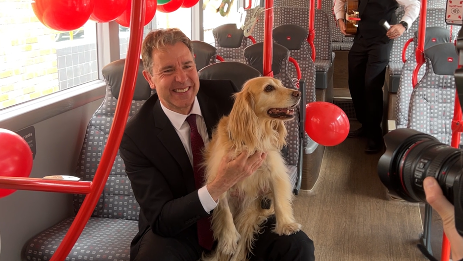 Dan Norris on a bus with a dog on his lap, having his photo taken