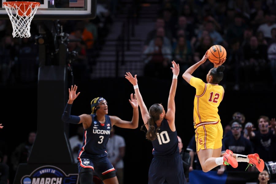 Southern California guard JuJu Watkins (12) shoots as UConn forward Aaliyah Edwards (3) and Nika Muhl (10) defend during the first half of an Elite Eight college basketball game in the women’s NCAA Tournament, Monday, April 1, 2024, in Portland, Ore. (AP Photo/Howard Lao)