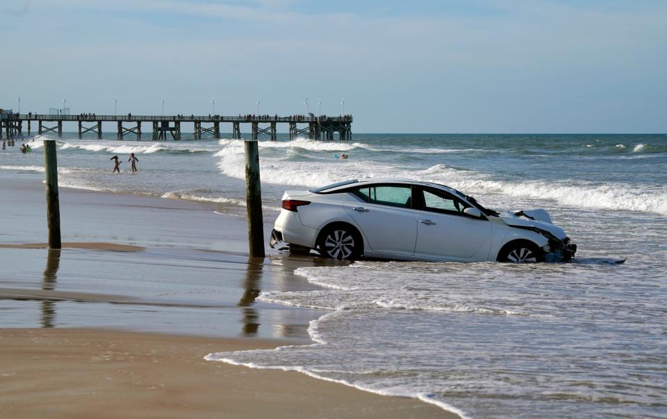 A car sits in the ocean after crashing through a beach toll booth in Daytona Beach, Sunday, July 24, 2022.