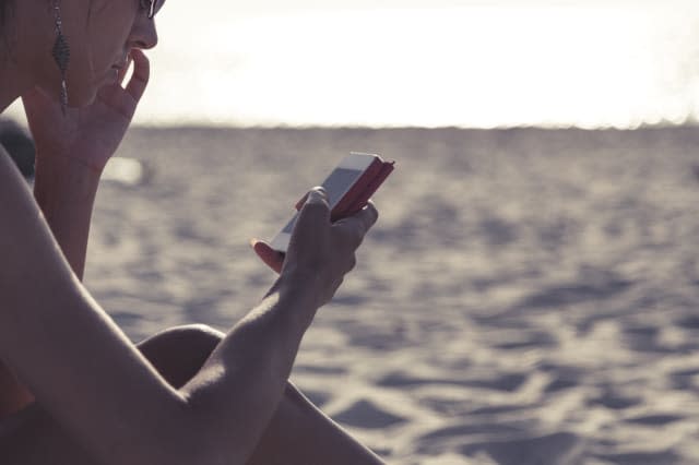 young girl on the beach, typing os smartphone