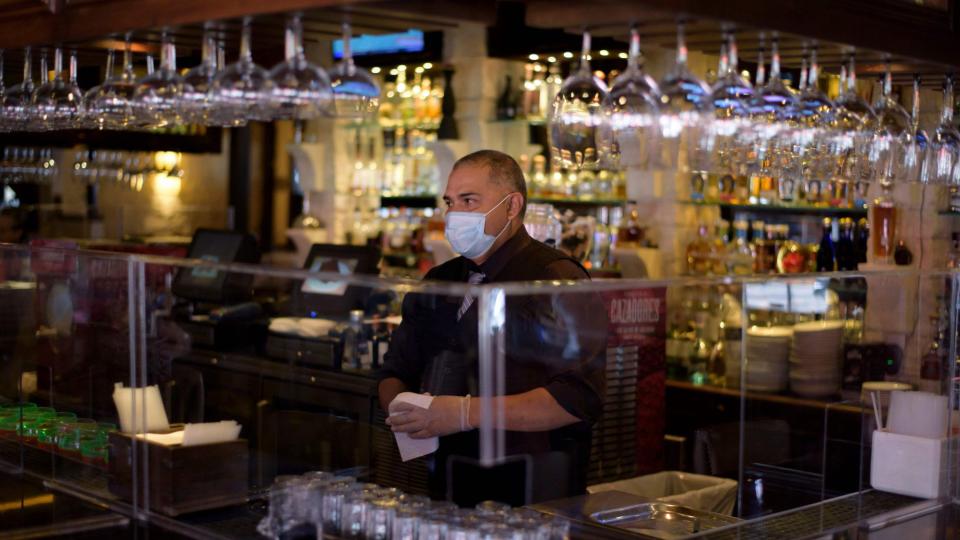 A bartender at Arnaldo Richards' Picos wears gloves and a mask while taking orders amid the coronavirus pandemic May 1, 2020 in Houston, Texas.