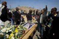 A group of men sing and raise their fists in salute at a coffin containing the body of one of the 34 striking miners killed by police, on August 31, 2012