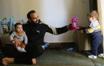 Mohamed Abdallah holds his biological son Soliman as he plays with Dawood, an orphan he sponsors, in their home in Cairo