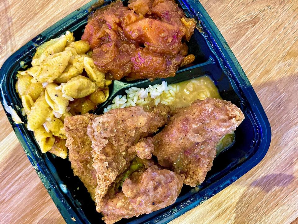Turkey chops with rice and gravy, macaroni and cheese and candied yams in an open takeout container